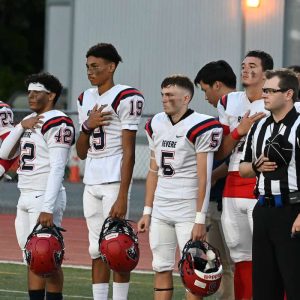Members of the Revere Patriots stand at attention during the National Anthem in the season opener of the high school football season.