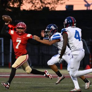 Tide QB Carlos Rodrigues tries to hold off a Highlander rusher during the Everett’s trouncing over Somerville at Veterans Memorial Stadium on Friday night.  (Advocate photo by Emily Harney)