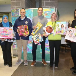 Shown from left: Assistant Principal Nicole Cascetta, Assistant Director of Diversity, Equity and Inclusion (DEI) Asmaa Abou-Fouda, Mayor Patrick Keefe, DEI Director Steven Morabito, Principal Rachel Shanley, and Reading Specialist Gina Petrone accepted toys.