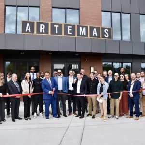 WELCOME HOME: Mayor Carlo DeMaria, who is joined alongside community leaders, project partners and residents, cuts the ribbon to celebrate the grand opening of Artemas.