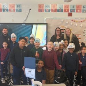 Asani Anderson is surrounded by his teacher, Ms. Andrews, Superintendent Dianne Kelly, Principal Rachel Shanley, Officer Brenes, K9 Charlie and his very proud classmates.