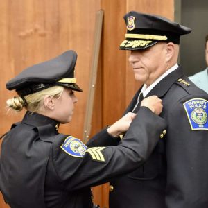 Police Chief Paul Strong’s daughter, Lauren, is shown pinning his Chief badge to his uniform.