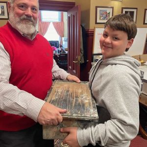 A HEAVY LOAD: Saugus Public Schools Superintendent Michael Hashem and Brody Crabtree, 10, a fifth-grader at the Belmonte STEAM Academy, carry the time capsule that was planted in the old Saugus High School built in 1954. Brody is the son of Town Manager Scott C. Crabtree. (Courtesy Photo to The Saugus Advocate)