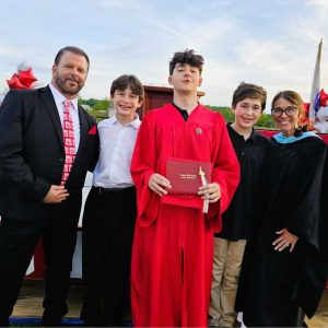 A MEMORABLE GRADUATION: Last Friday night was special for Saugus School Committee Chair Thomas Whittredge and his family at the Saugus High School graduation. Joining Whittredge (left) and his wife, Elizabeth (far right), were their three sons – Noah, Brody (who graduated with this year’s class) and Cole. Noah, a freshman, plays in the band and performed at his brother’s graduation. Elizabeth is a Special Education teacher at the High School and attended as a faculty member. (Saugus Advocate photo by Mark E. Vogler).