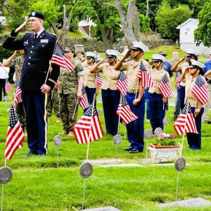 A MEMORIAL DAY SALUTE: Chaplain (Major) Scott McGowan, the keynote speaker at this year’s Saugus Memorial Day Ceremonies, and members of the Lynn English High School MCJROTC stood at attention as a bugler played Taps at Riverside Cemetery last Saturday. (Saugus Advocate photo by Mark E. Vogler)