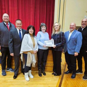 A TRIBUTE TO HER DAD: Carla J. Moschella (center) displays a copy of the “Commemorative book” she wrote and compiled about her dad, the late Carmine Moschella, a Saugus artisan who built numerous pieces of furniture and other wooden gifts for the town. Pictured from left to right are Town Manager Scott C. Crabtree, Selectman Michael Serino, Selectman Corinne Riley, Carla Moschella, Board of Selectmen Chair Debra Panetta, Board of Selectmen Vice Chair Jeff Cicolini and Selectman Anthony Cogliano (Saugus Advocate Photo by Mark E. Vogler)