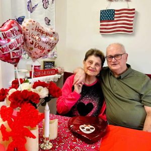 ABUNDANT LOVE: Saugus residents Ed and Linda Helein, who have been married for 57 years, embraced as they sat at a Valentine’s Day-themed table. Tomorrow, Saturday, Feb. 14, lovers around the world will celebrate Valentine’s Day. Ed said he celebrates Valentine’s Day “Every day.” (Photo courtesy of Joanie Allbee)