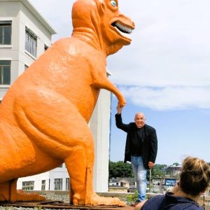 AN ANGRY DINOSAUR OWNER: Developer Michael Barsamian, seen shaking hands with his friend, said he shares a special bond with the Town of Saugus by keeping this old Route 1 landmark in a special spot at Essex Landing. But he doesn’t like the way the town has treated him lately, prompting him to file a federal lawsuit last week. (Courtesy photo to The Saugus Advocate)