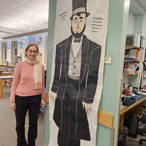 Abe Lincoln towers among all presidents featured at the Saugus Public Library. Here Amy Melton, Head of Children's Services at the library, looks up to a poster of the tall president. (Saugus Advocate photo by Mark E. Vogler)
