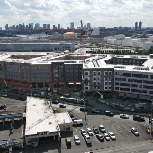 An aerial view of Anthem Everett – located at 35 Garvey St. in Everett’s Commercial Triangle District – with Boston’s skyline in the background. The building, which will rise six stories and include ground floor retail space, recently celebrated its topping out and is scheduled to deliver in mid-2024. (courtesy photo)