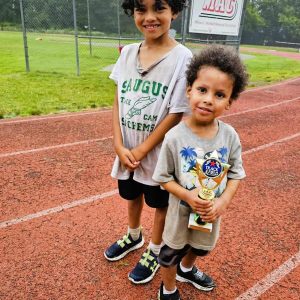 BROTHERS ON THE RUN: Leo Hobbs, 7 and his brother Tye, 4, were among 44 Saugus kids who participated last summer in the Saugus Sachems Track Camp. They also got to hold the second-place trophy that their team won while competing against 14 other teams in the Fourth Annual Cranston League for Cranston’s Future (CLCF) Summer Showdown in Cranston, R.I. They took home 19 first-place awards. (Saugus Advocate File Photo by Mark E. Vogler)