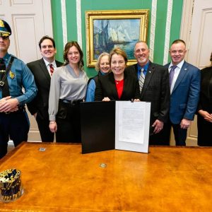 CELEBRATING A NEW LAW: Left to right: Mass. State Police Lieutenant Colonel Mark Cyr, Massachusetts Senate Public Safety Chair Senator John Cronin, Sadie Bossi, Sue Bossi, Governor Maura Healey, State Police Lt. Donald Bossi, State Police Association of Massachusetts President Brian Williams and state Rep. Jessica Giannino at a recent bill-signing ceremony in the governor’s office. (Photo Courtesy of Josh Qualls from the Governor’s Office)