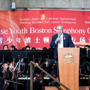 State Representative Joe McGonagle is shown addressing the audience at Boston City Hall following a performance by the Beijing Golden Sail Junior Orchestra.