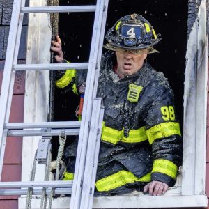 A firefighter is shown exiting to the ladder from inside the Fairmont Street home.