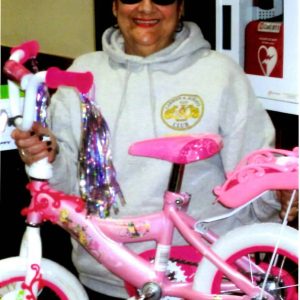 Volunteer Dotty Doucette holds a girl’s bicycle that members assembled just in time for Christmas. (Photo courtesy of Wayne Matewsky)