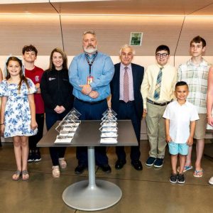 The community of Saugus celebrates their Unsung Heroes at Saugus Middle High School on Wednesday Evening, from left, Maeve Chiaravalloti, Ava Newbury, Ava Najem, Ryder Cutelis, Brooke Miles of WIN Waste Innovations, Superintendent Mike Hashem, President of Business Education Collaborative Peter Rossetti Jr, Alex Wallace, Kai Torres, Arthur Freitas, and Nevaeh Rogers.