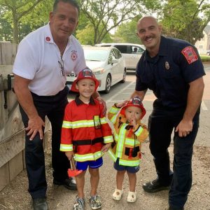 FIREFIGHTERS WITH KIDS: Left to right: Captain Billy Cross and Firefighter Matt Massone of the Saugus Fire Department were a big hit with kids during their Aug. 15 visit to the Saugus Iron Works National Historic Site. They offered a fun learning experience to Caleb Figueroa, 5, who attends kindergarten at the Veterans Early Learning Center, and his little brother Mateo. (Courtesy photo to the Saugus Advocate by Amy Melton)