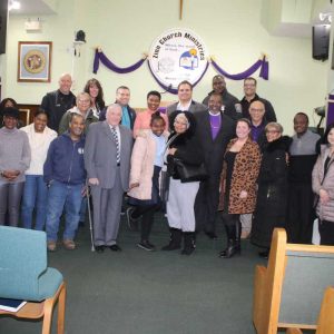 Those in attendance took a group photo. Front row, shown from left to right: Robert Price, Sheila Lee-Caldwell, Marcia Brown, Dominique Gooding, Duncan Brock, Councillor-at-Large John Hanlon, Haley Drane, Simone Holyfield, Councillor-Elect Holly Garcia, Vilma Torres, Rev. Joseph Chacha Marwa, Kathleen Parker, Frank Parker, Bishop Regina Shearer. Second row, shown from left to right: Dotty Amos, Nena Price, Senator Sal DiDomenico, Yanique Louis, Mayor Carlo DeMaria, Rev. Bishop Robert Brown, and Councillor Al Lattanzi. Top row, shown from left to right: Peter Sikoro, Kim Nicolo, Jermaine Bellard, and City Councilor-Elect Anthony DiPierro.