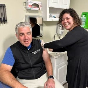 Dr. Steve Landers gets his annual flu shot from Hebrew SeniorLife colleague Kiara Ortega. (Photo credit: Michele Rezendes, Hebrew SeniorLife)
