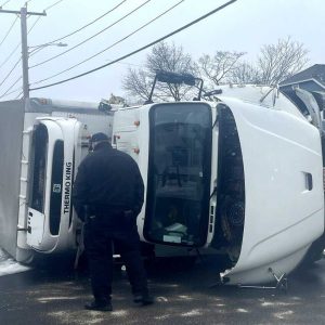 An Everett police officer inspects the truck that was involved in a crash with another vehicle last Friday morning on Lynn Street. (Advocate photo)
