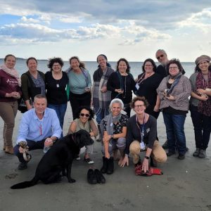 Israeli rabbis and chaplains gathered for a photo at Revere Beach across from Jack Satter House, where they met with residents as part of an impactful week of learning, healing and cultural exchange. Pictured from left to right: Back row: Rabba Claudia Marbach, Guy Gardy, Chaplain Meirav Ben-Shoshan, art therapist/mindfulness and meditation teacher Sara Roizen, Rabbi Beth Naditch, Rabbi Mira Regev, Rabbi Iris Bondi, Dr. Renana Ravitzky Pilzer, Rabbi Lior Nevo, Chaplain Nir Golan, Rabbi Eliana Jacobowitz, Rabbi Orit Raz, Rabbanit Sarah Segal-Katz and Rabbi Dr. Iris Yaniv; front row: Rabbi Elisha Wolfin, Rabbi Chen Ben-Or Tsfoni, Chaplain Yael Yisrael, Rabbi Karen Landy and Tamari, the service dog. (Courtesy photo)