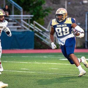 LOOKING FOR AN OPENING— Malden High junior tight end Earl Fevrier (88) looks for an opening so he can get some more yards.
