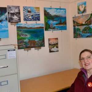 Local artist Joanie Allbee sits in front of her Mini Alaska Art Exhibit now on display at the Saugus Historical Society. Allbee, who lived in Alaska, dedicated the exhibit to Saugus native Gustavus Vasa Fox, who was credited with negotiating the deal that enabled the United States to purchase Alaska from Russia. (Courtesy photo to The Saugus Advocate)