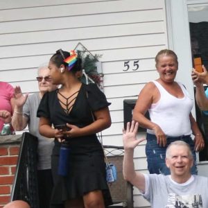 San Rock 2022: Marie Swansen greeting the Procession as it passes by her front porch — her beloved family right by her side.