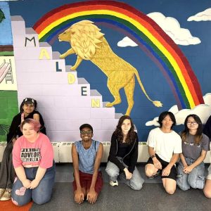 MYSEP supervisor and Salemwood School Art educator Emily Gonzalez (back row, far right) and her students are shown in front of their latest creation, a mural in Cafeteria “A” at Malden High School. (Courtesy/Malden Public Schools)