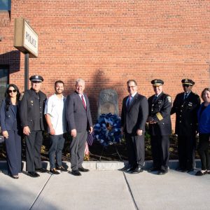 Sergeant Kenneth Kelley, Ward 2 Councillor Stephanie Martins, Officer Eric Rizza, Ward 3 Councillor Anthony DiPierro, State Representative Joe McGonagle, Mayor Robert J. Van Campen, Police Chief Paul Strong, Bishop Robert G. Brown, Ward 4 Councillor Holly Garcia and Ward 1 Councillor Michele Capone stand in front of the memorial wreath during the Everett Police Department Memorial Service.