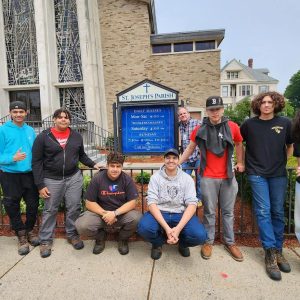 Some of the students who participated in the project to redesign and refurbish the sign at St. Joseph’s Parish in Malden stand with the sign. (Courtesy Northeast Metro Tech)