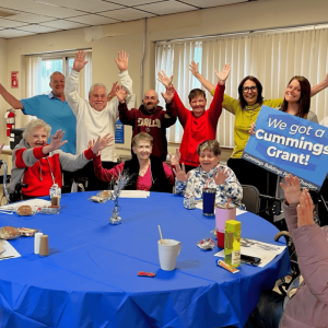 News of the Cummings Grant drew cheers from MVES staff as well as residents of 630 Salem St. in Malden, one of the first sites where the Housing Wellness Program was established. Pictured with residents are MVES Wellness Nurse Janelle Wilkins (holding the sign), Resident Services Coordinator Terri Fitzgerald (left of Janelle) and Development Specialist Jan Brodie (right of Janelle). (Courtesy photo)