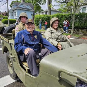 PARADE GRAND MARSHAL: Eugene Decareau, a 95-year-old Korean War Era veteran, rides in a jeep accompanied by World War II reenactors.