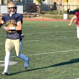 SCRAMBLING: Junior quarterback Billy Gavin scrambled down the sideline looking for an open man against BC High on Friday. (Courtesy/Malden HS Athletics)