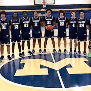 The Malden High School Varsity Basketball Team includes, from left, Assistant Coach Dan Jurkowski, De’Shawn Bunch, Ryan McMahon, Jamal Hakkaoui, Captain Wyatt Dessert, Shawn Sekamwa, Colin Okoth, Kaua Fernandes Dias Valadares, Jason Minervini, Chris Macdonald, Yasser Belatreche, Aidan Brett, Jose Ferreira and Head Coach Don Nally. (Photos/Courtesy of Malden Athletics)