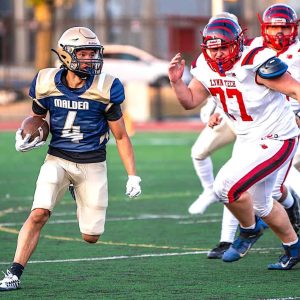 RECORD RETURNS: Malden High senior Johnson Huynh (4) sees some daylight on one of his record-setting punt returns. Huynh returned two punts for touchdowns in Malden’s 27-20 win over Lynn Tech in its regular season and home opener game, tying a school record. (All Advocate Photo by Henry Huang)