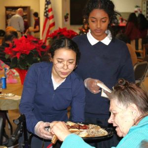 Marina Silva, of Medford, and Madot Guesh, of Malden, were among the students serving dinner at the holiday party presented by MVRCS at 630 Salem St. in Malden. (Courtesy photo)