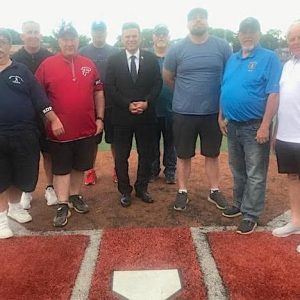 A tribute honoring Bob Rotondi was held on Monday at Rotondi Field in the first game played since his passing, on the day of his funeral and interment. Sharing in the ceremonies were, from left, Dave Allan, Malden Recreation Coordinator Joe Levine, Malden Babe Ruth Field Director/Treasurer and Flames manager Deano Summers, Knights assistant coach Marc Freni, Malden Mayor Gary Christenson (who delivered Bob Rotondi’s eulogy at the cemetery earlier that day), Knights assistant coach Andy Scarano, Malden Babe Ruth League Player Agent Chris Kosuk, Malden DPW Director and former Babe Ruth manager Bob Knox and Malden Babe Ruth League President Greg Lucey. (Advocate Photos)