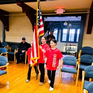 PRESENTING THE COLORS: Three members of Saugus Youth Football and Cheer U-10 Cheering Squad officially opened this year’s Annual Town Meeting by carrying the American flag into the second-floor auditorium of Town Hall Monday night. (Saugus Advocate photo by Mark E. Vogler)