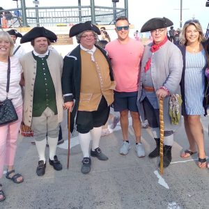 Ward 1 Councillor Joanne McKenna, Michael Lepage, Revolution 250 Executive Director Jonathan Lane, Mayor Patrick Keefe, Tom Coots, Rep. Jessica Giannino and Ward 5 Councillor Angela Guarino-Sawaya with reenactors on Revere Beach on Saturday.
