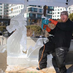 ICE SLAYER: The Revere Beach Winter Wonderland Festival kicked off for the first-time last weekend and featured some talented artists including professional ice sculptor Tony Perham, of White River Junction, Vermont, shown here pretending to slay his creation, “Vera The Sea Dragon” for the Advocate photographer. (Advocate photo by Tara Vocino)