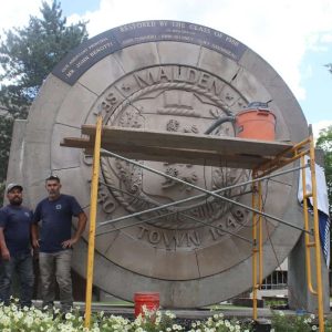 Shown from left to right, are Victor Mejias, Jr., Antonio Telule and Nelson Martinez, who volunteered to restore the city seal, on Monday outside of Malden High School.