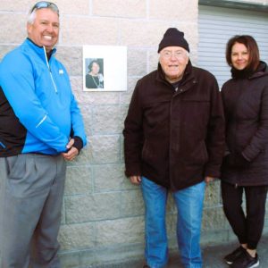 THE DAVIS FAMILY: Members of the family of the late Carolyn Davis stand near the sign that honors her many hours of volunteer work running the snack bar at World Series Park, which recently celebrated its 20th anniversary. Pictured from left to right are Carolyn’s son Glen, her husband Bob and her daughter Rachel. (Saugus Advocate photo by Tara Vocino)