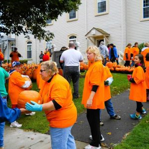 THE ORANGE GLOW REVISITED: The Pumpkin Patch is set to return for the 23rd year tomorrow (Saturday, Sept. 27). Church members and community volunteers from a previous year are shown unloading the “Pumpkin Truck” on the lawn of First Congregational Church in Saugus Center. (Courtesy photo to The Saugus Advocate)