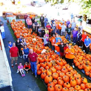 “THE ORANGE GLOW”: Volunteers from a previous year who unloaded pumpkins at the First Congregational Church “Pumpkin Patch” in Saugus Center. Volunteers are needed on September 23 to help with this year’s unloading. (Courtesy photo to The Saugus Advocate)