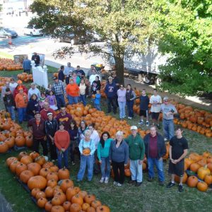 “THE ORANGE GLOW”: Volunteers from a previous year who unloaded pumpkins at the First Congregational Church “Pumpkin Patch” in Saugus Center. Volunteers are needed on Sept. 21 to help with this year’s unloading. (Courtesy photo to The Saugus Advocate)