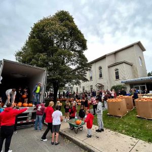 THE PUMPKIN PATCH AT SAUGUS CENTER: Players, cheerleaders and coaches from Saugus Youth Football and Cheer and students from Pioneer Charter School and Saugus High participated in unloading the Pumpkin Truck on Saturday at First Congregational Church. (Courtesy Photo to The Saugus Advocate)