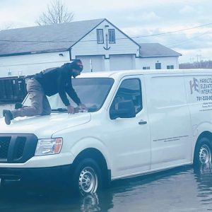 TRAPPED IN THE WATER: Todd “TJ” Patterson found himself stuck on the hood of a company van during the recent flooding outside of Hamilton Elevator Interiors, Inc. on Belair Street. (Courtesy Photo of Glenn Bowie to The Saugus Advocate)