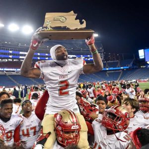 Jason Maitre of Everett celebrates with the MIAA Div. 1 Super Bowl trophy after defeating Xaverian 35-10 at Gillette Stadium, Saturday, Dec. 2, 2017.