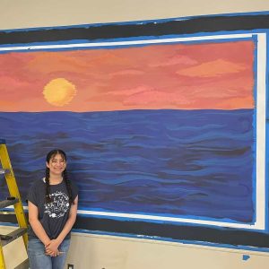 RHS student Yasmi Granados Flores in front of her mural at the Revere Senior Center.